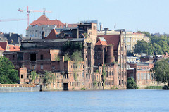 Historische Hafenarchitektur, verfallene Backsteingebäude - Fabrik Anlagen mit abgetragenem Schornstein an der Oder im Hafen Stettin.
