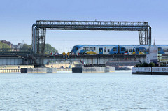 Drehbrücke / Eisenbahnbrücke mit Versorgungsleitungen an der Westoder in Stettin, ein Zug fährt in die Stadt ein.