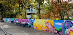 Marktplatz im im Hamburger Stadtteil Bramfeld, buntes Graffiti an einer  Mauer, im Hintergrund das Haus der Jugend.