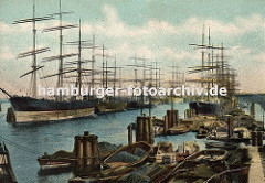 Die Segelschiffe liegen in der Mitte des Hafenbeckens und beim Kai im Hamburger Segelschiffhafen (ca. 1900); im Vordergrund Schuten, die mit Kohle, Kisten oder anderer Ware beladen sind.