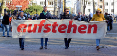 Aktionstag der überparteilichen Sammlungsbewegung Aufstehen - Start der Demonstration mit dem Motto Würde statt Waffen auf dem Platz der Republik in Hamburg Altona. Transparten mit der roten Aufschrift "aufstehen".