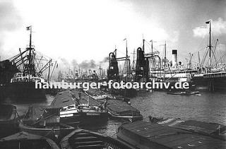 Historische Bilddokumente aus dem Hamburger Hafen.  Blick in den  Hamburger Segelschiffhafen ca. 1930, links wird ein Frachtschiff am Americakai mit Kränen entladen - Motorschiffe und Lastkäne liegen mit ihrer abgedeckten Ladung im Hafenbecken.