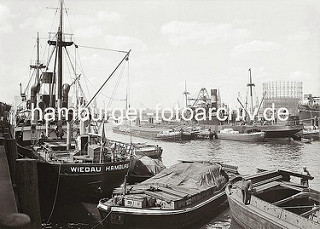 Historische Hafenmotive aus dem Hamburger Fotoarchiv. Frachtschiffe liegen im Segelschiffhafen - der Güterumschlag findet zur Kaiseite mit Kränen statt; zur Wasserseite werden die Waren mit bordeigenen Ladebäumen auf Schuten und Elbkähne geladen