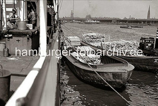 Historische Hafenmotive aus dem Hamburger Fotoarchiv.   Schuten haben am Amerikakai des Segelschiffhafens längsseits eines Frachters festgemacht - eine Ladung Kanthölzer wird auf die Lastkähne gelöscht. Auf der gegenüber liegenden Seite der