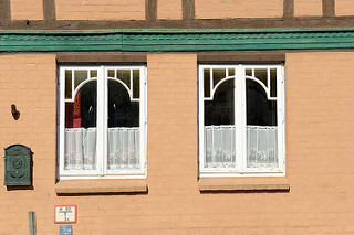 Fenster mit aufgesetzter Verleistung / Zierleisten und Gardinen mit Stickereien an einem Wohnhaus in der Mühlenstraße von Boizenburg/Elbe