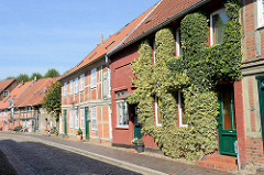 Denkmalgeschützte Wohnhäuser in der Großen Wallstraße von Boizenburg/Elbe; die Fassade eines der Gebäude ist dicht mit Efeu bewachsen. Die Straße ist mit Kopfstein- Pflaster gepflastert.