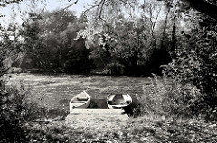 Uferidyll an der Wilhelmsburger Dove Elbe  in Hamburg Wilhelmsburg, schwarz-weiß Fotografie - zwei Ruderboote liegen am Holzsteg.