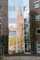 Spiegelung der Sankt Bonifatius Kirche  in der Glasfassade eines Gebäudes; Bilder aus Hamburg Wilhelmsburg - Architektur der Stadt.