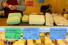 Wochenmarkt auf dem Marktplatz in Hamburg Rothenburgsort; Marktstand mit Käse, z.  B.  Trüffelkäse, Wasabi und eine Käsesorte mit dem Namen Sommersprosse.