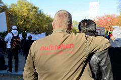 Aktionstag der überparteilichen Sammlungsbewegung Aufstehen - Sammelplatz der Demonstration mit dem Motto Würde statt Waffen auf dem Platz der Republik in Hamburg Altona. Ein Demonstrant trägt eine Jacke mit der Aufschrift Aufstehen die Sammlungsbewe