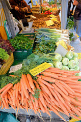 Marktstand mit Gemüse auf dem Wochenmarkt am Moorhof im Hamburger Stadtteil Poppenbüttel; im Vordergrund liegen frische Möhren und Kohlrabi.
