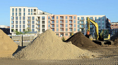 Baustelle mit großen Sandhaufen  auf dem Gelände des ehemaligen Güterbahnhofs Hamburg Altona - im Hintergrund neu gebaute Wohngebäude.