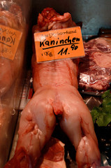 Marktstand einer Schlachterei auf dem Wochenmarkt in Hamburg Wilhelmsburg / Stübenplatz; ganzes Kaninchen ohne Fell.