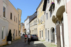 Wohn- und Geschäftshäuser, teilweise aus dem 16. Jahrhundert in der Steiner Landstraße von Stein an der Donau /Krems. Schmale Gasse mit Kopfsteinpflaster und parkenden Autos sowie Radfahrer.