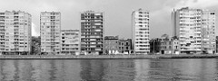 Blick über die Maas auf den Quai Saint-Léonhard in Lüttich / Liège. Einstöckige Altbauhäuser der Gründerzeit stehen zwischen Hochhäusern am Ufer der Maas.
