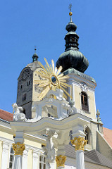 Johannes Nepomuk-Denkmal auf dem Rathausplatz in Krems / Stein; die  Figur des Heiligen steht unter einem  Baldachin. An den Postamenten sind Engelsfiguren zu sehen und im Baldachin Putten mit Strahlenkranz.  Dahinter die Kirchtürme der Pfarrkirche H