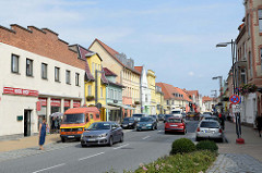 Blick in die Geschäftsstraße / Einkaufstraße lange Straße Bützow; die Hausfassaden sind in unterschiedlichen Farben dekoriert.