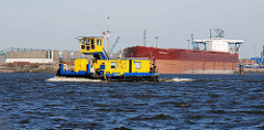 Ein Schubschiff fährt Elbe abwärts, dahinter ein Massengutfrachter am Kirchenpauerkai im Hamburger Hafen.