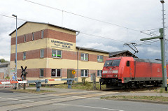 Gebäude mit Eisenbahnsymbol an der Fassade des Bahnbetriebswerks Wismar; schlichtes Verwaltungsgebäude.