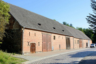 Lang gestrecktes Speichergebäude mit großen Holztoren in der Angermünder Straße von Oderberg; die Straße ist mit Kopfstein gepflastert.