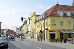 Blick in die Geschäftsstraße / Einkaufstraße lange Straße Bützow; die Hausfassaden sind in unterschiedlichen Farben dekoriert.
