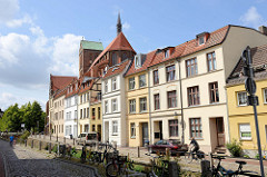 Wohnhäuser am Mühlenbach in Wismar, dahinter   das Kirchenschiff und Kirchturm der Sankt Nikolaikirche.