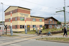 Gebäude mit Eisenbahnsymbol an der Fassade des Bahnbetriebswerks Wismar; schlichtes Verwaltungsgebäude sowie historischer Fachwerkschuppen - Fassade vom Ringlokschuppen.