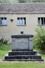 Kugeldenkmal für die im Ersten Weltkrieg in der Kriegsgefangenschaft verstorbenen Kameraden Gartz/Oder; dahinter ein leerstehendes Gebäude.
