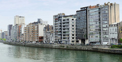 Wohnhäuser am Ufer der Maas in Lüttich / Liège; moderne Hochhäuser und historische Altbauten stehen dicht gedrängt nebeneinander.