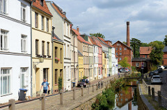 Blick von der Schweinsbrücke in der Hansestadt Wismar auf die Mühlengrube / Mühlenbach und die historischen Wohnhäuser mit unterschiedlich farbige Fassade. Im Hintergrund das historische Gebäude der Stadtmühle, die 1856 errichtet wurde und als Indu