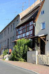 Wohnhäuser in unterschiedlichem Baustil in der Berliner Straße von Oderberg. Ein denkmalgeschütztes Fachwerkgebäude steht eingequetscht zwischen anderen Häusern.
