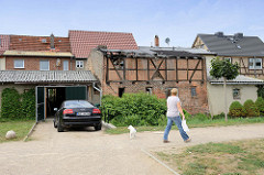 Mit Wellblech gedeckte Garage neben einem verfallenen Fachwerkschuppen am Ufer der Warnow in Bützow.