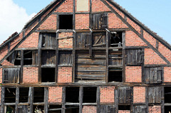 Altes Speichergebäude, Trocknungsscheune für Tabakblätter in Gartz / Oder. Giebel eines Fachwerkhauses mit zerbrochenen Holztüren für einzelne Trocknungs-Böden