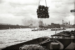 Eine Schute ist mit verpackten Rohrstühlen beladen - eine Ladung der Fracht hängt über dem Schiff am Kran des Kamerunkai vom Hamburger Indiahafen. Im Hintergrund rechts hat ein Frachter vor dem Schuppen 52 des Australiakais festgemacht.