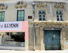 Alt und neu, historisches Gebäude mit Sandsteinfassade; die linke Fassade ist für ein Geschäft verputzt und den pink gestrichen - die rechte Seite zeigt die ursprüngliche Ansicht.