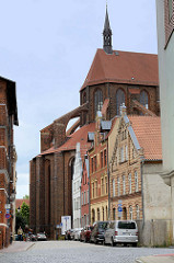 Historische Wohn- und Geschäftshäuser in der Wismarer Straße Hinter dem Chor, dahinter das Kirchenschiff der  Sankt Nikolaikirche.  Die Kirche wurde von 1381-1487 als Kirche der Seefahrer und Fischer erbaut. Sie gilt als Meisterwerk der Spätgotik un