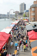 Flohmarkt am Ufer der Maas in Lüttich / Liège; Marktstände mit Zeltdach, Passanten schlendern über den Markt.