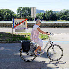 Ortsausgang Krems/Stein - Ortsschild an der Donaupromenade, schnell fahrende Radfahrerin.