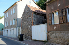 Architektur in der Stadt Oderberg, Wohnhaus mit Feldsteinfundament und Holz Luken, daneben ein Speichergebäude mit Feldsteinmauer.