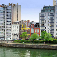 Wohnhäuser am Ufer der Maas in Lüttich / Liège; moderne Hochhäuser und historische Altbauten stehen dicht gedrängt nebeneinander.