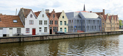 Blick über den Kanal Langen Kai zu historischen Wohnhäusern im typischen flämischen Architekturstil mit Treppengiebeln an der Straße Potterierei in Brügge .