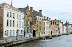 Wohnhäuser in unterschiedlichen Baustilen an der Straße Sint Annarei  - auf der gleichnamigen Gracht fährt ein Boot mit Touristen durch die Altstadt von Brügge.