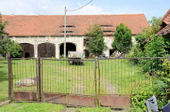 Leerstehende landwirtschaftliche Gebäude /  Scheune mit großen Toreinfahrten und schmalen Dachgauben in   Pieszyce / Peterswaldau.