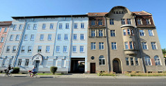 Mehrstöckige Wohnhäuser in Eberswalde, teilweise restauriert mit farbig abgesetzter Fassade sowie Wohnhaus mit Rauhputzfassade.
