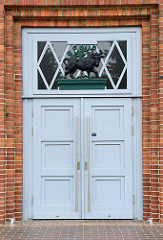 Eingangstür der Sporthalle /  Kongresshalle in der Speicherstraße von Güstrow; geschnitzter schwarzer Stier im Oberlicht.