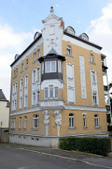 Denkmalgeschütztes Wohnhaus / Eckgebäude in der Straße Am Anger in Altenburg. Eine männliche und weibliche Skulptur - Atlant und Karyatide - stützen einen Erker an der Hausecke.