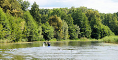 Ruhe und Entspannung auf dem Finowkanal in Brandenburg - dicht stehen die Bäume am Kanalufer. Ein Kanut fährt mit seinem Paddelboot kanalaufwärts.