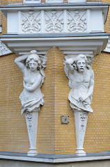 Eine männliche und weibliche Skulptur - Atlant und Karyatide - stützen einen Balkon eines denkmalgeschützten  Wohnhauses in der Straße Am Anger in Altenburg.