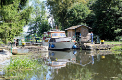 Die Schleusentore der Schleuse Ragöse am Finowkanal wurden vom Schleusenwärter von Hand geöffnet, ein Sportboot verlässt die Schleusenkammer.