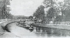 Historische Fotografie vom Finowkanal, ein Frachtkahn wird von einem Schlepper gezogen  - an Land stehen Kinder und blicken auf das Schiff.